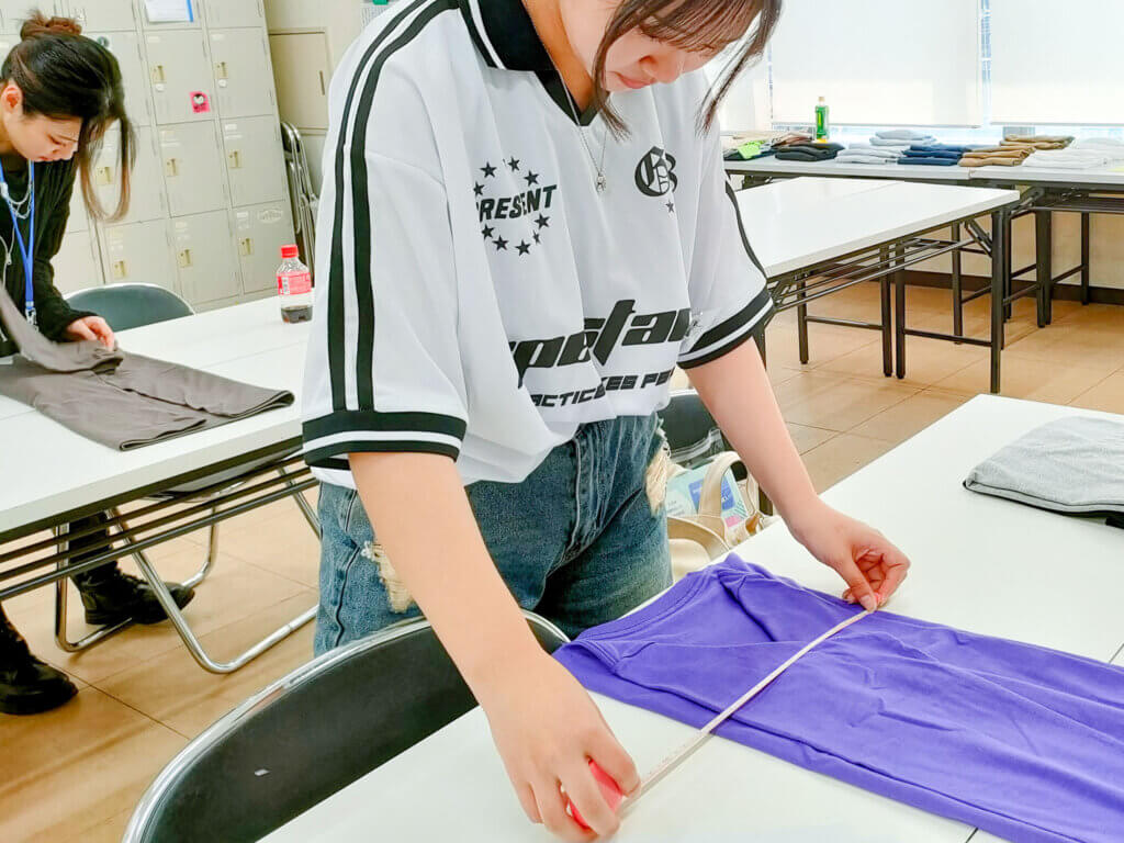 メジャーを使いながら、Tシャツを綺麗に畳んでいる様子。