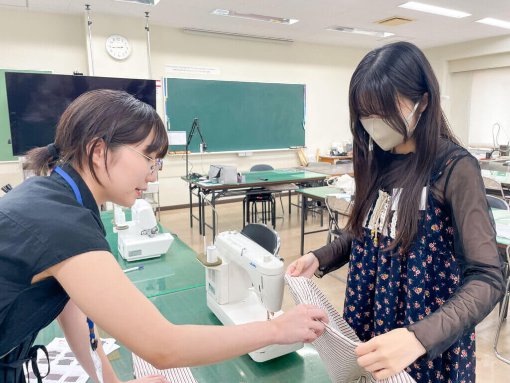 在校生の先輩がオープンキャンパス参加者の方に、作業の方法を教えている様子。